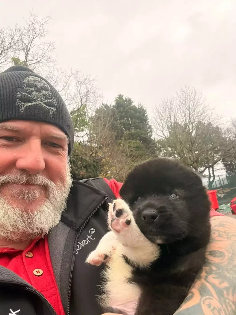 fluffy black-and-white pup waving a tiny paw for the camera